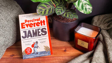 James book next to a peacock plant and candle